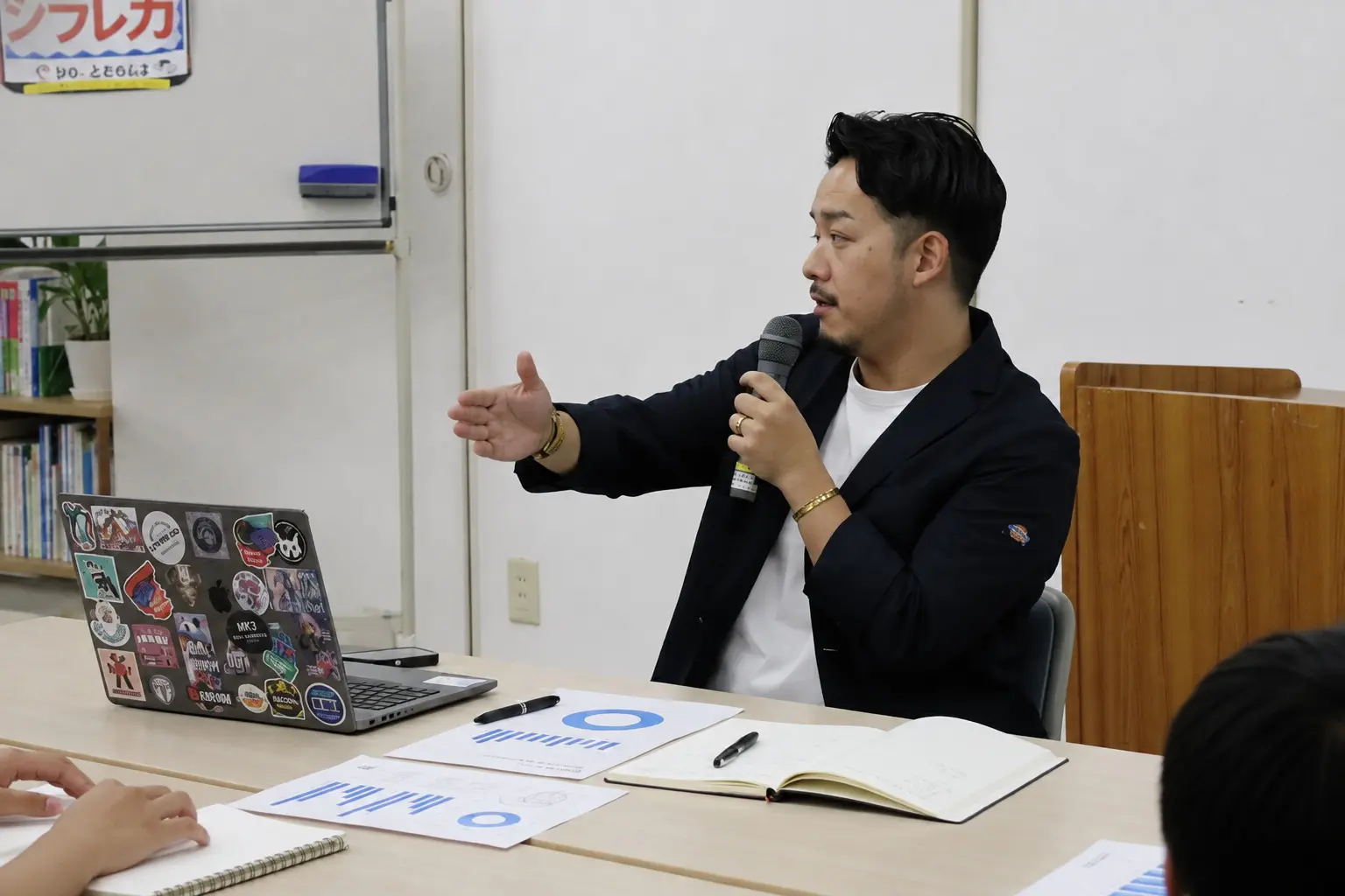 跡部耕司がマイクを持ち、対話しながら説明する様子